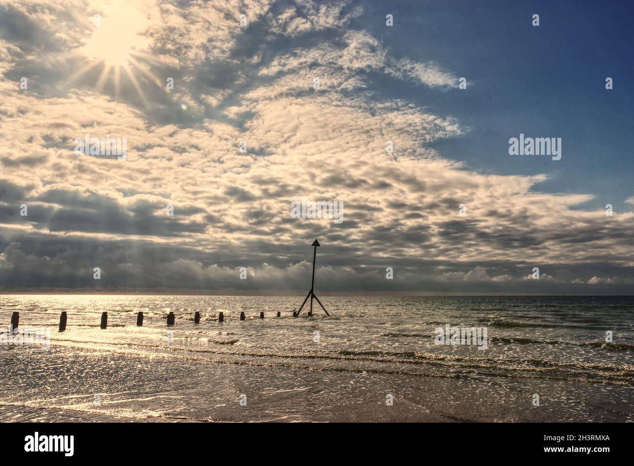 Sunrise over a sandy beach with groyne Stock Photo