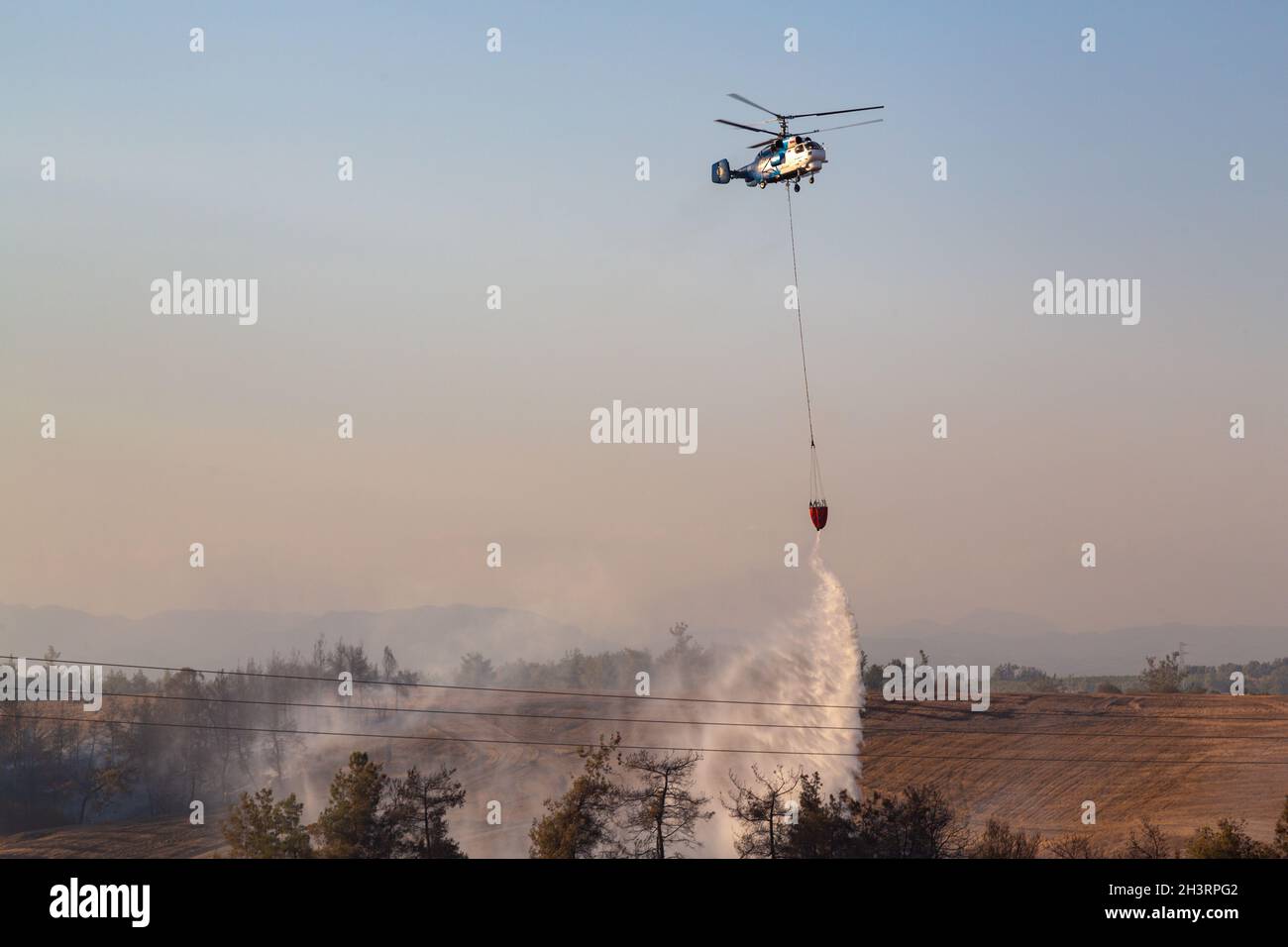 Wildfire helicopter pours water on fire. One of the most effective ways to fight forest fires. Stock Photo