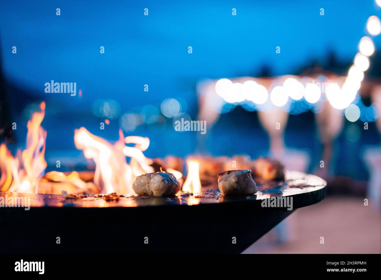Closeup of pieces of fish fillet on a bowlshaped grill with a fire