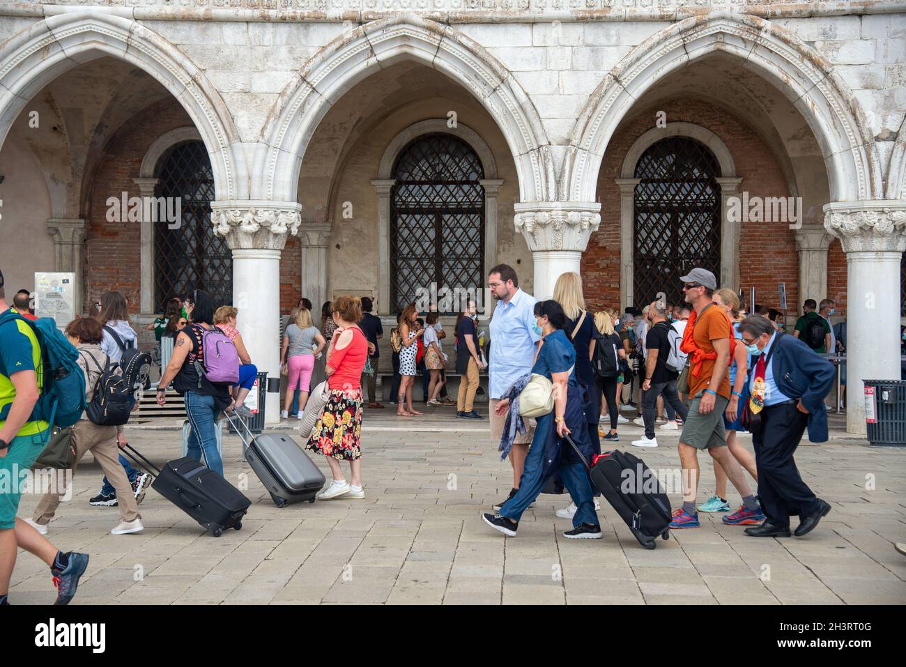 tourists wit rolling suitcases passing Palazzo Ducale at San Marco
