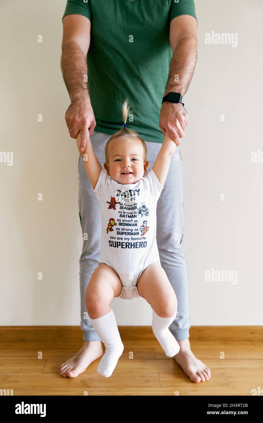 Little girl swinging on daddy's arms in the room Stock Photo Alamy