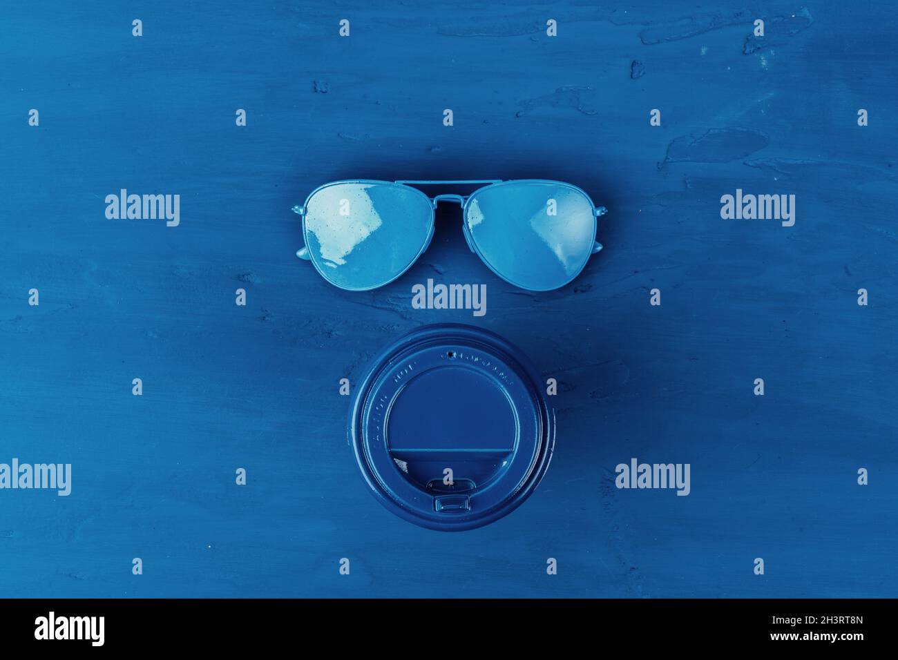 Top view of takeaway coffee cup with aviator sunglasses on classic blue ...