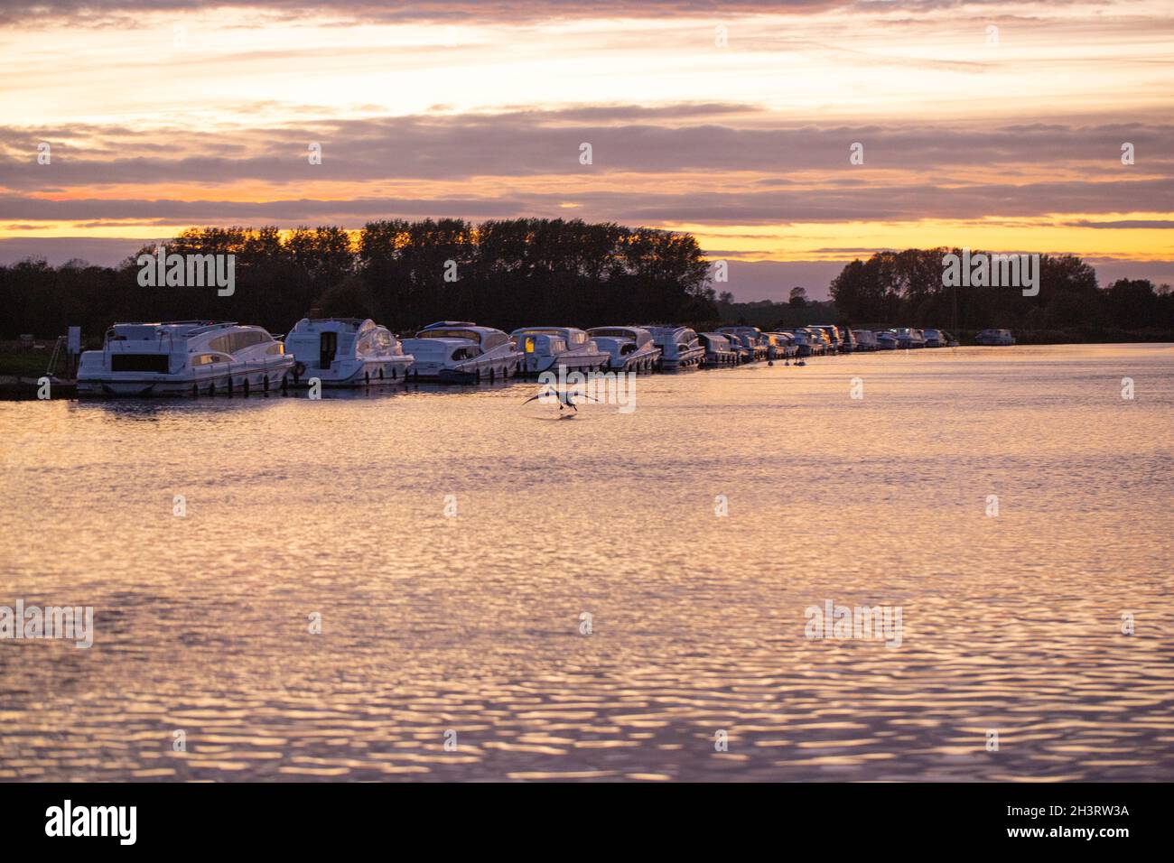 Evening sunset. Colourful cloud layers reflected on the surfaceof River Bure, Acle Bridge, Broadland, Norfolk, National Park. Holiday, vacation, cruis Stock Photo