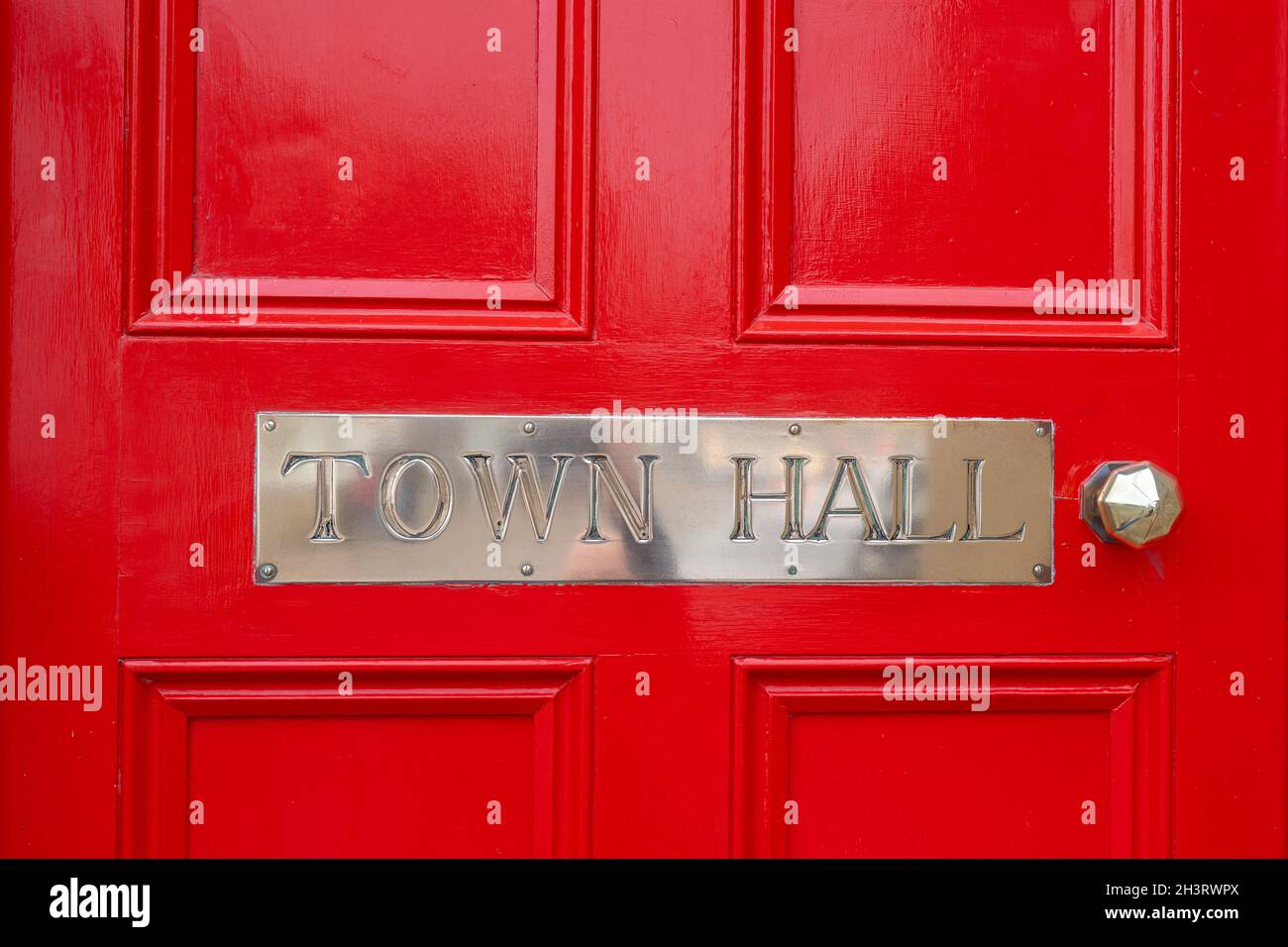Town Hall silver metal sign. Polished chrome steel sign on bright red wooden door, shiny and clean stainless steel handle. Capital letters town hall Stock Photo