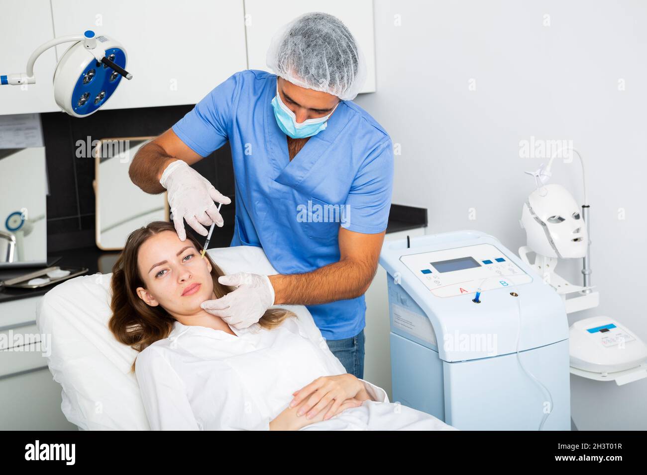 Beautician performing face contouring injections to female patient