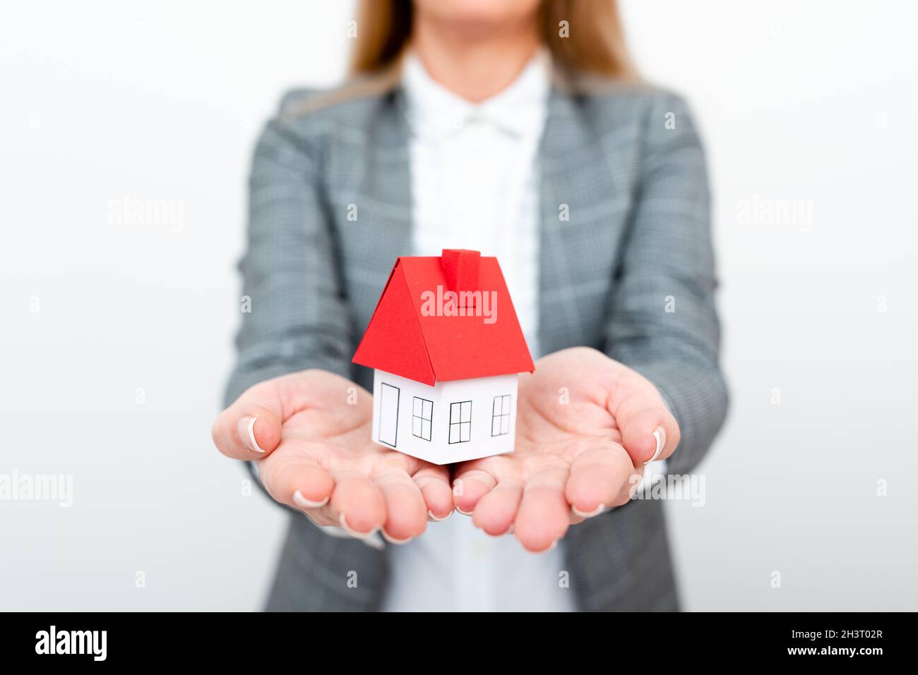 A Lady Holding Home In Business Outfit Presenting Possibility Of Owning Your Own Real Estate. Buying House Or Moving New Insuran Stock Photo