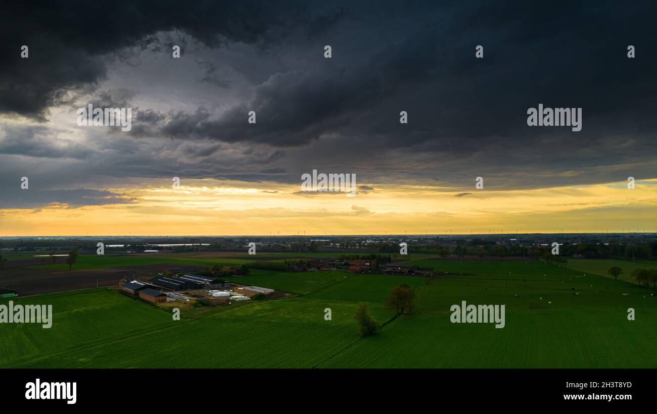Aerial landscape of countryside with colorful storm clouds. Extreme thunderstorm over a farm and agricultural fields and road. Stock Photo