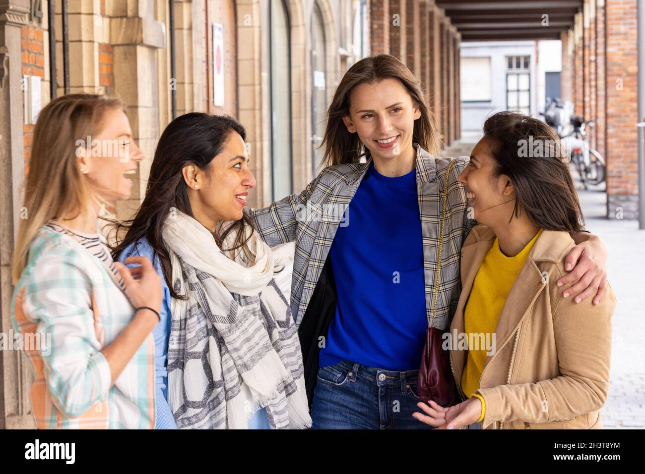 Lifestyle portrait of a diverse multiethnic group of attractive young woman friends talking together and smiling, having fun out Stock Photo
