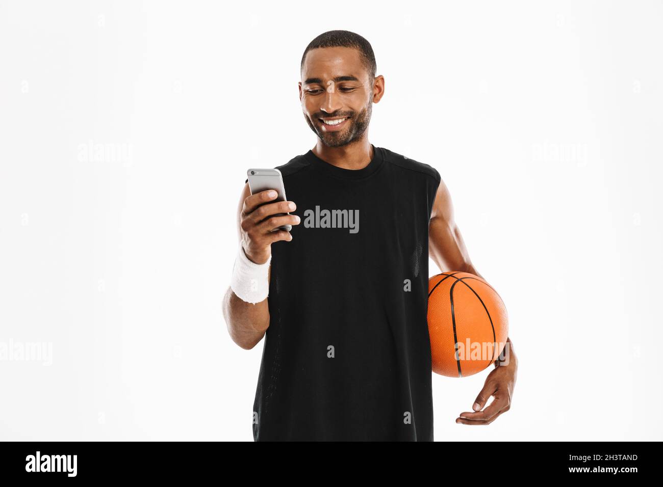Happy african young basketball player standing talking on mobile phone isolated on a white background Stock Photo