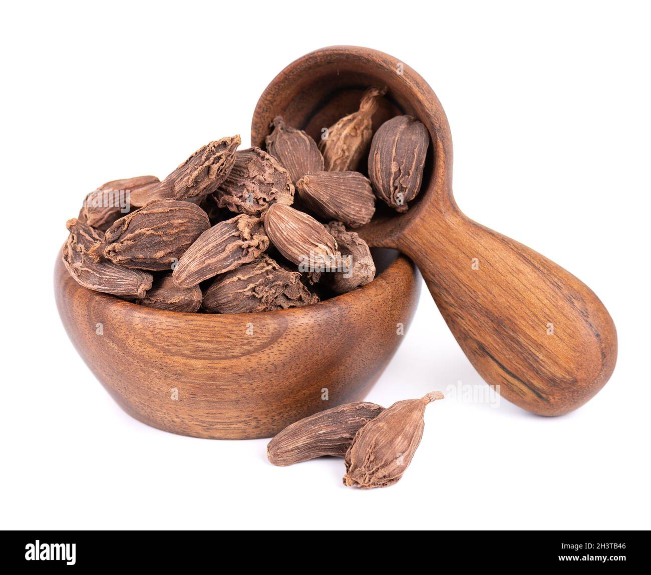 Heap of black cardamom pods in wooden bowl and spoon, isolated on white