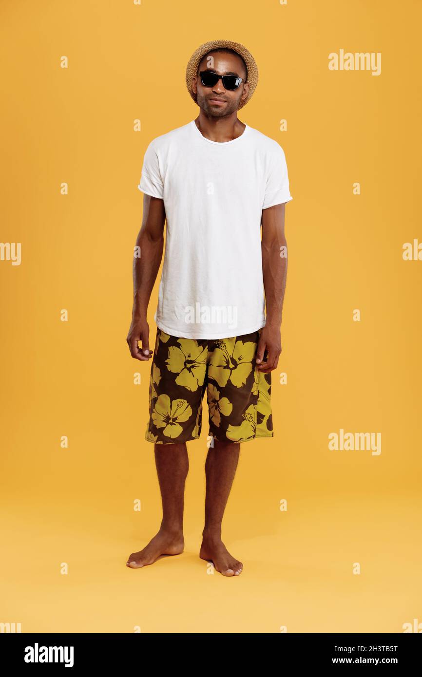 Front view of handsome young black man. Guy wear t shirt swimming trunks straw hat and glasses. Concept of summer beach vacation. Isolated on yellow Stock Photo Alamy