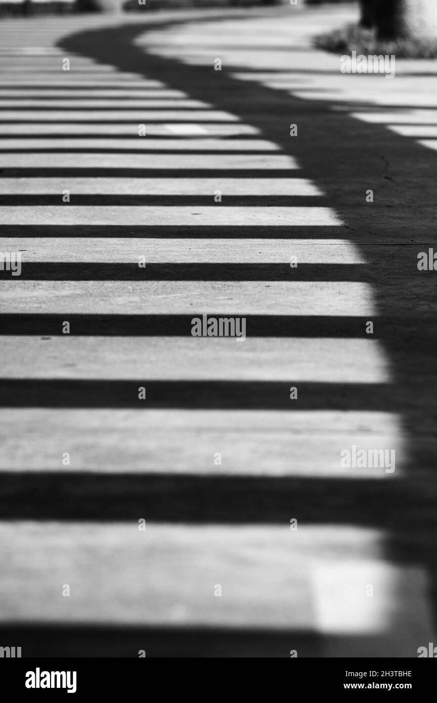 Grayscale shot with a vertical format outside of a shadow on the stairs Stock Photo
