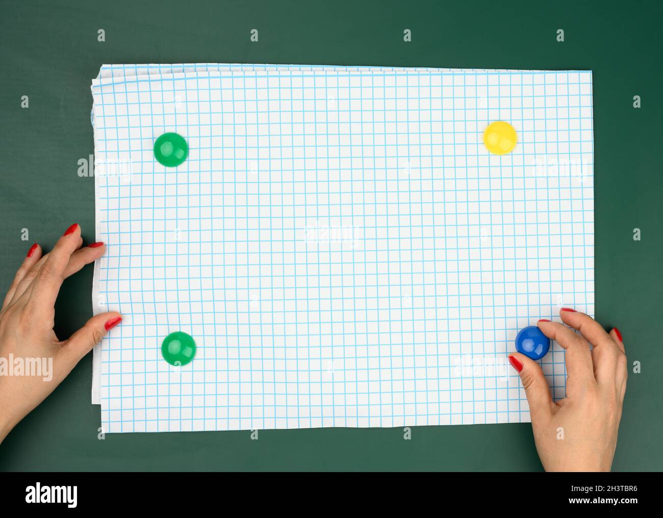 Two female hands fix a white blank sheet of paper in a box on a