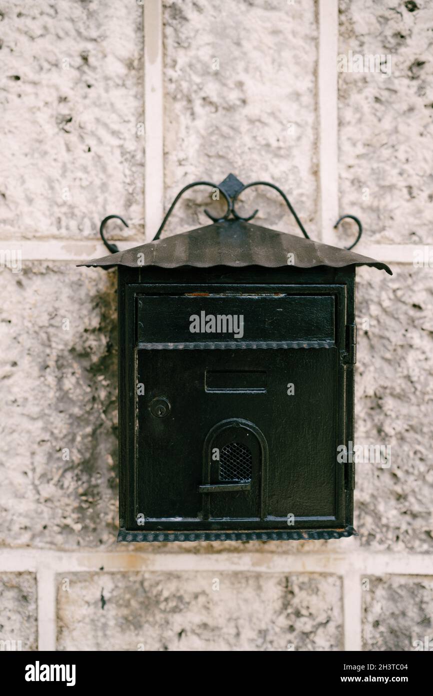 Close-up of a black metal mailbox on a stone wall. Stock Photo