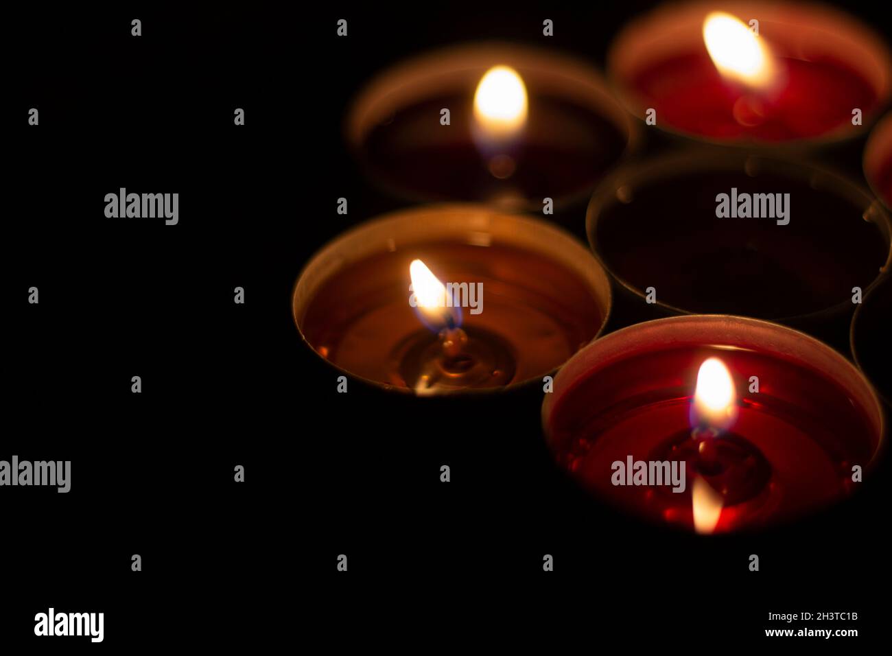 Candle flames in the dark. Candles burn with yellow fire. Liquid wax gradually melts Stock Photo