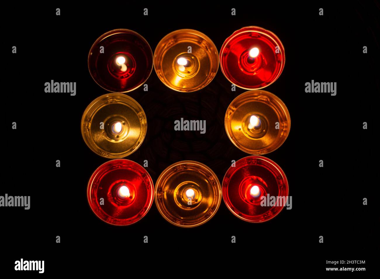 Square of candles. Candles burn in the dark. Orange wax and red wax