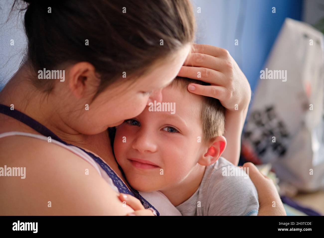 cute boy hugs his mother and looks at the camera Stock Photo