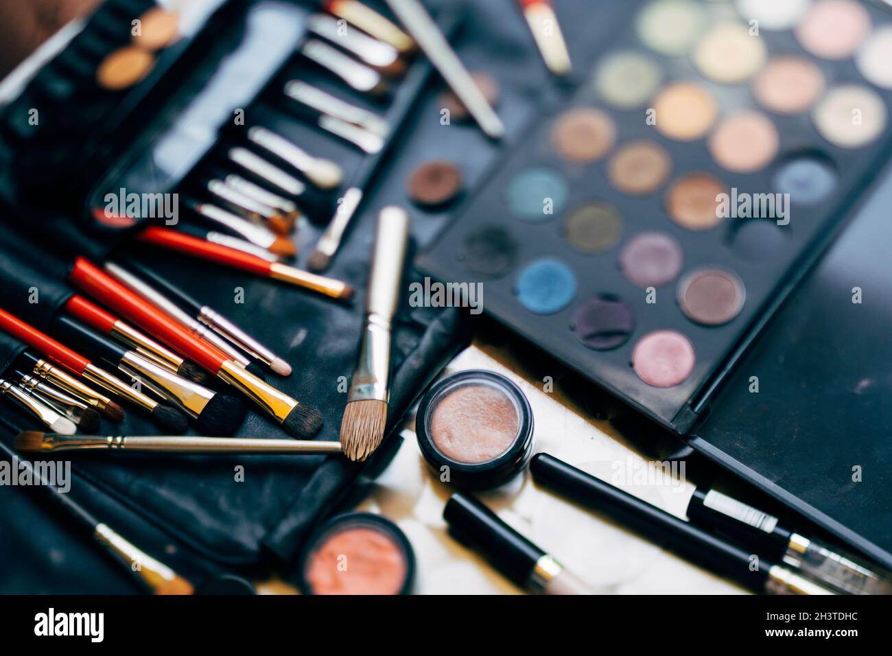 Makeup artist set. A palette of eyeshadows in different colors and a set of makeup brushes with blush in a black cosmetic bag. Stock Photo
