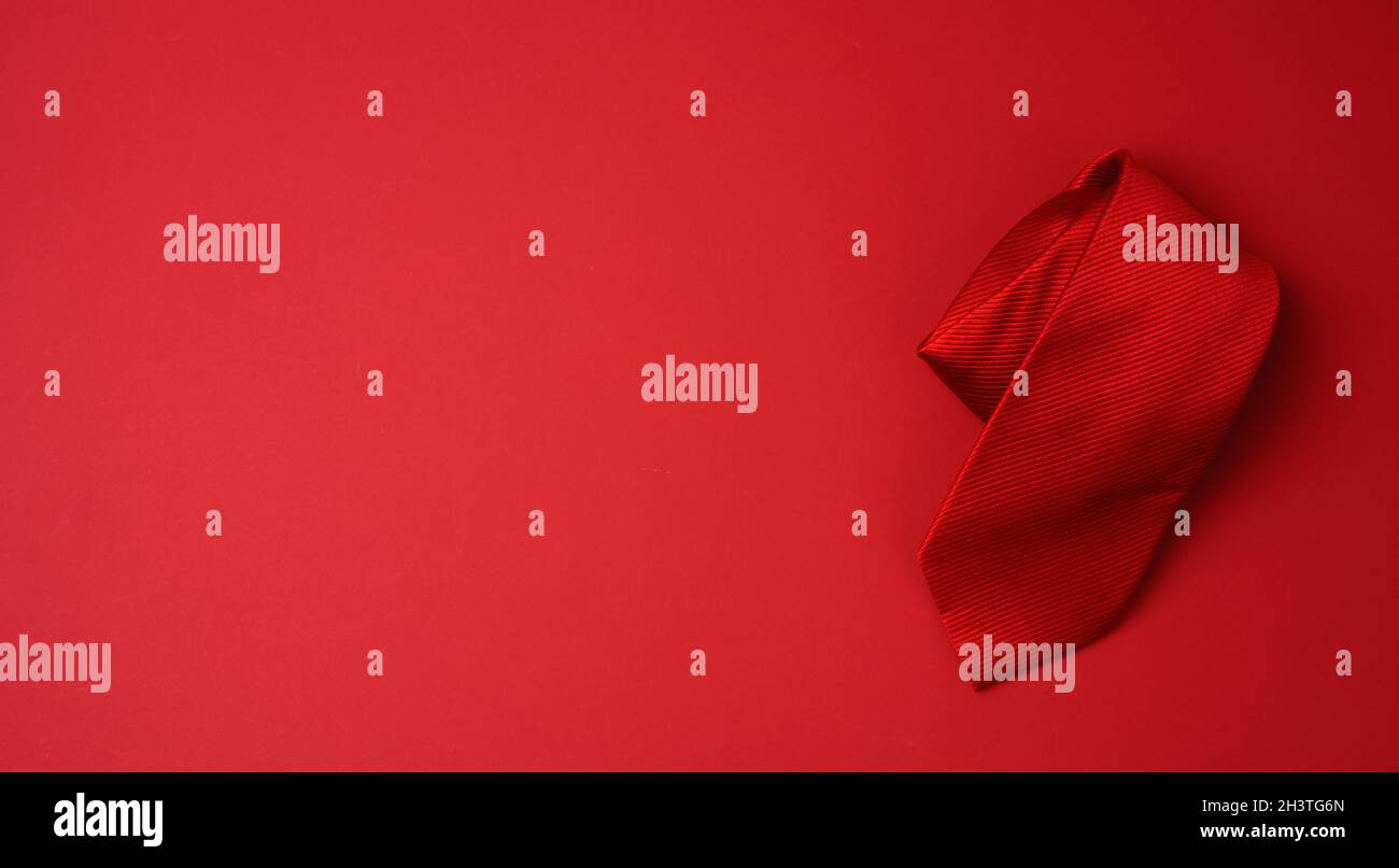 Twisted silk red tie on a red background Stock Photo