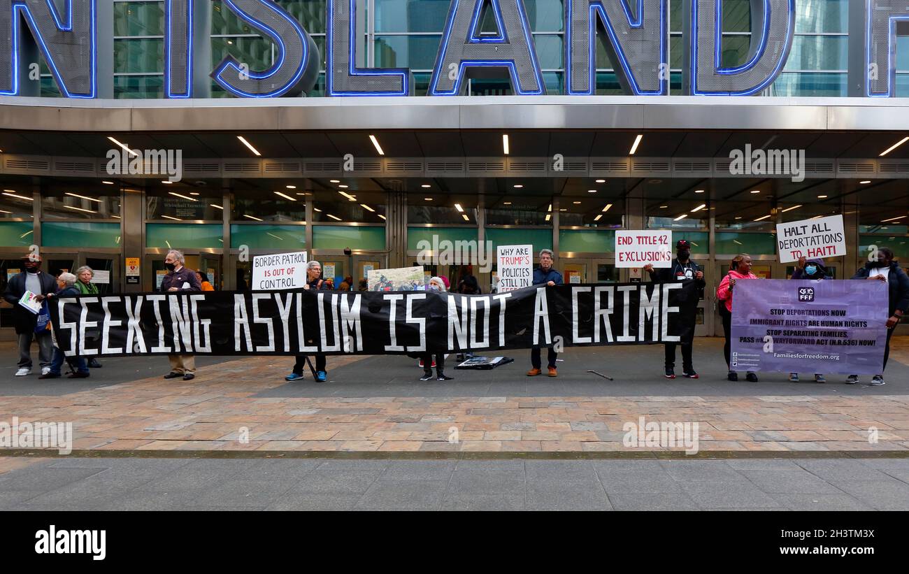 NYC, 28 Oct 2021. Activists from the group Families for Freedom unfurl a banner 'Seeking Asylum is Not a Crime' outside Staten Island Ferry. title 42 Stock Photo