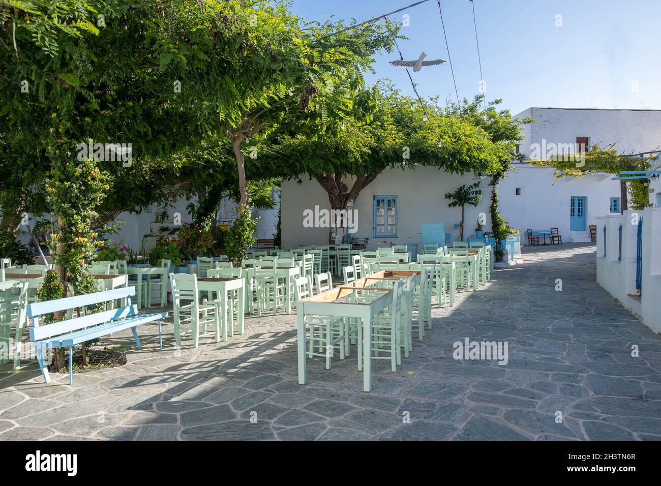 Greece, Folegandros island. Traditional outdoor cafe bar and tavern. Blue empty tables and chairs, Chora town square. Cyclades. Summer holidays destin Stock Photo
