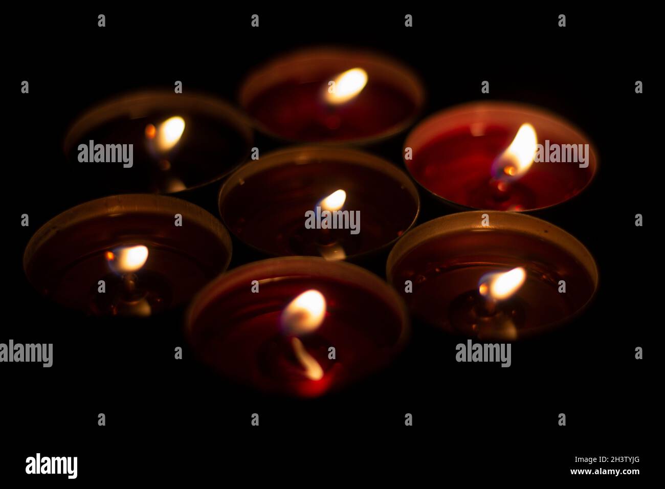 Candle flames in the dark. Candles burn with yellow fire. Liquid wax