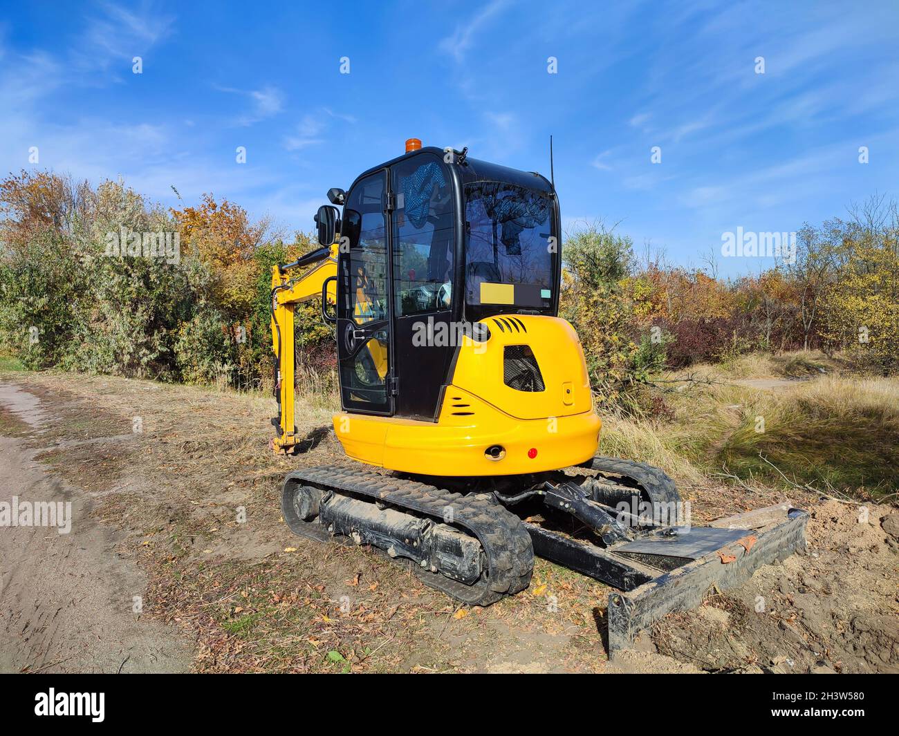 Modern yellow JCB mini digger or excavator performs excavation work outdoors Stock Photo