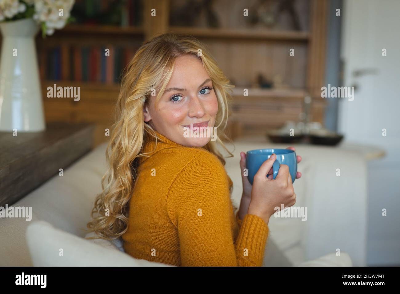 Portrait of happy caucasian woman sitting on couch in living room ...
