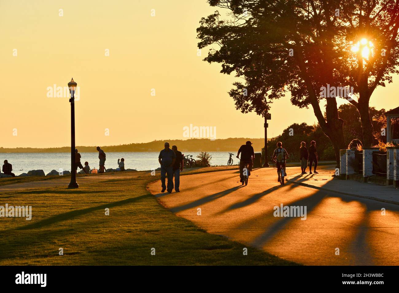 People gathering to watch golden sunset and bicyclists biking on road