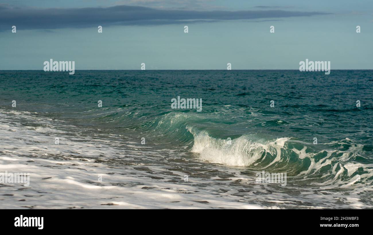 small wave crashing at a beach in crystal clear water Stock Photo - Alamy