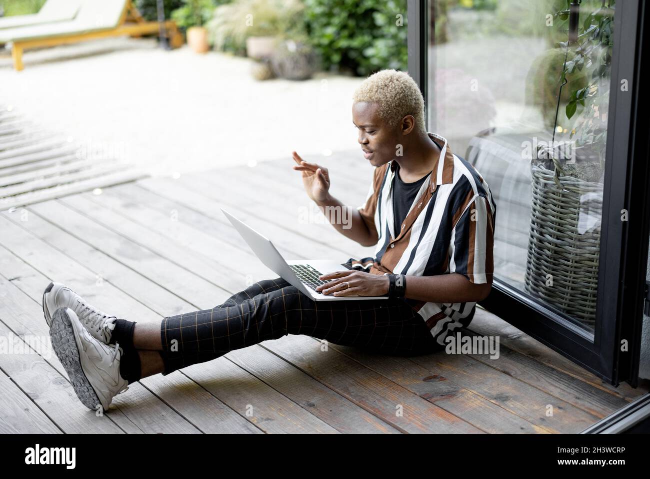 Black man using laptop computer on terrace at home Stock Photo