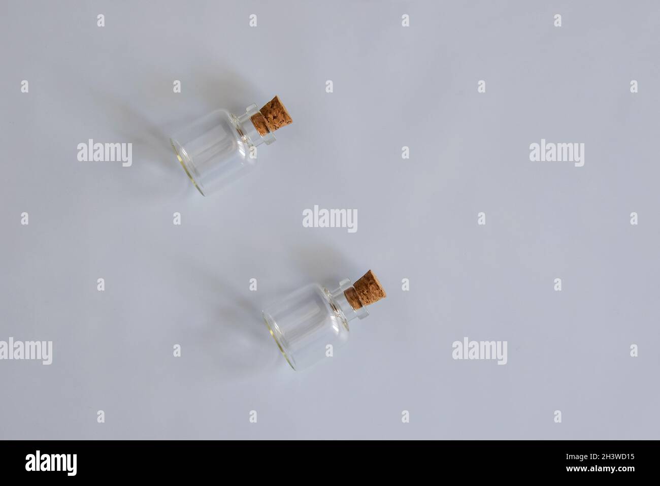 Two empty small glass bottles with cork stoppers on gray background. Side lighting. Horizontal photo. Copy space. Close-up. Selective focus. Stock Photo