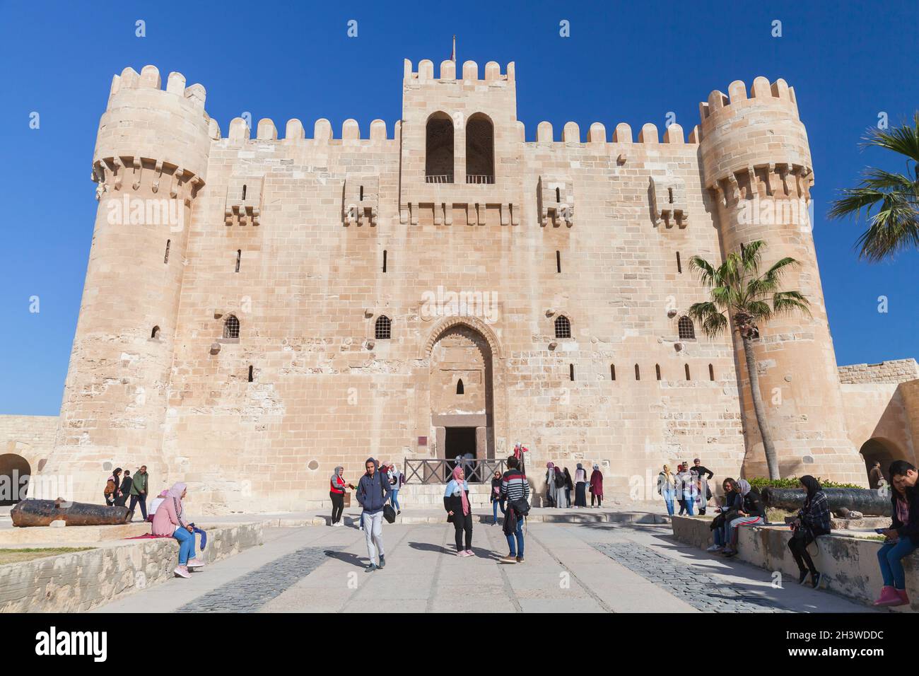 Alexandria, Egypt - December 14, 2018: Tourists walk in front of The Citadel of Qaitbay or the Fort of Qaitbay. It is a 15th-century defensive fortres Stock Photo