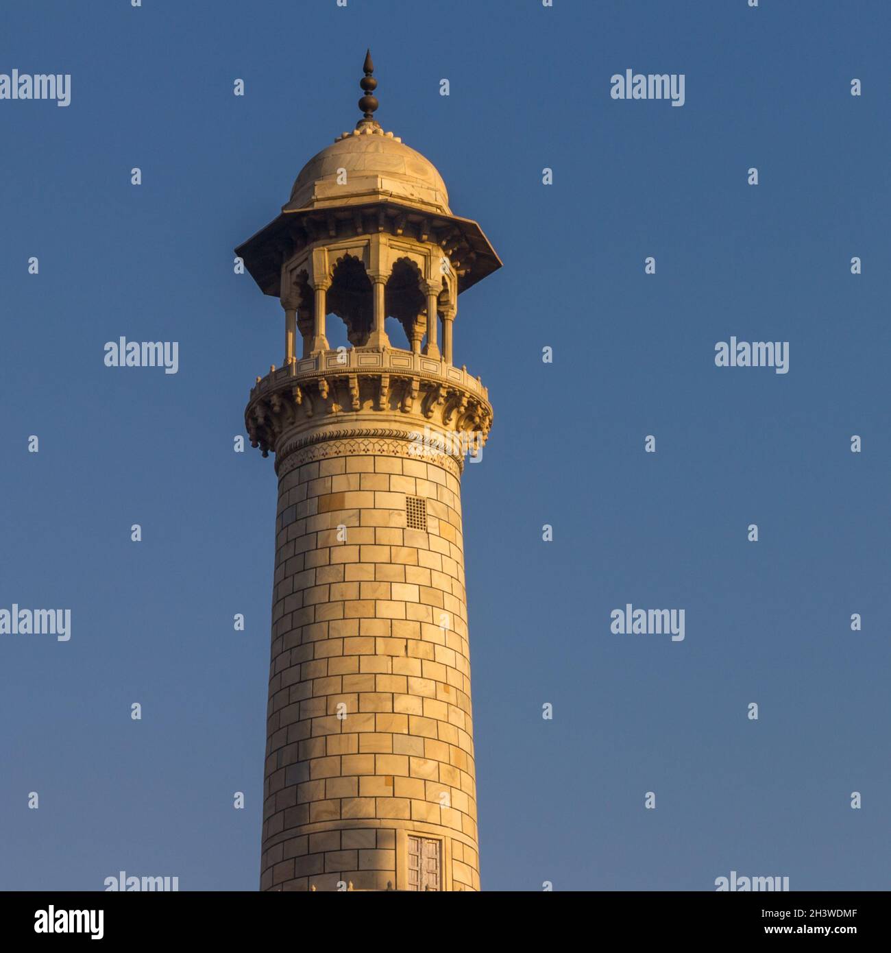 Taj Mahal's minaret lit by the warm rays of the rising sun Stock Photo