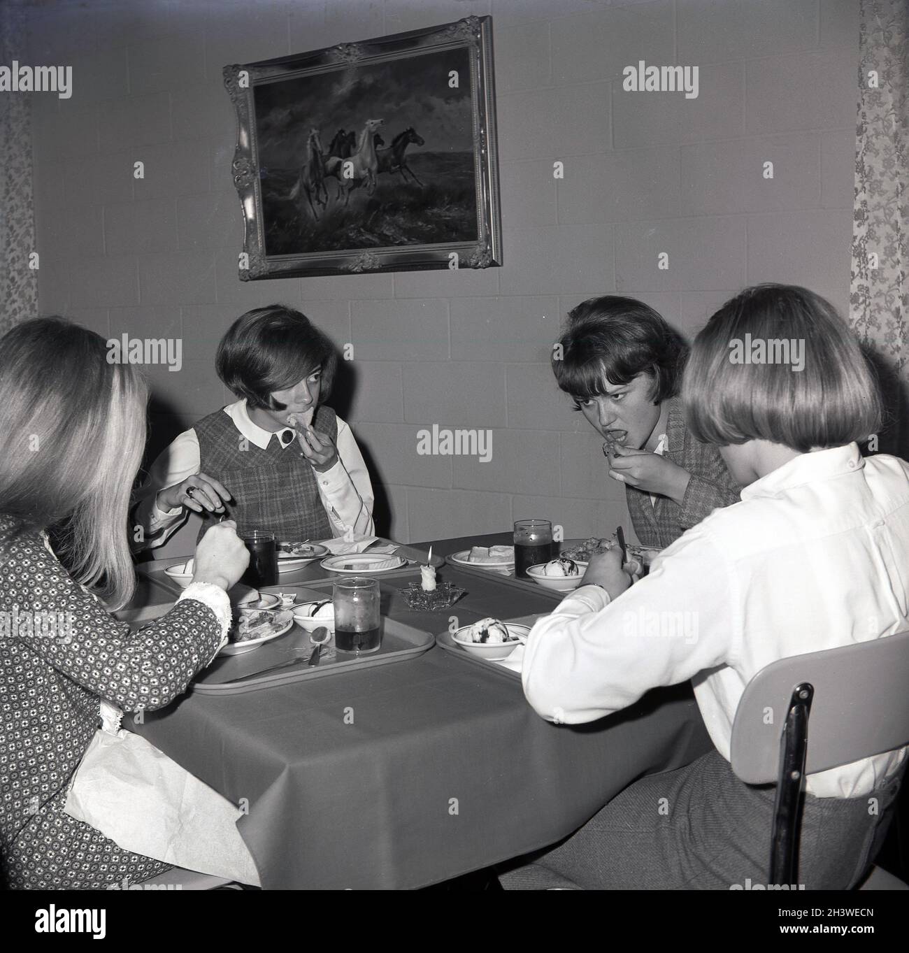 1960s, historical, four female college students sitting together at a table, with a tablecloth, with their trays of food, in a dining room, having their evening meal, Virginia, USA. Stock Photo