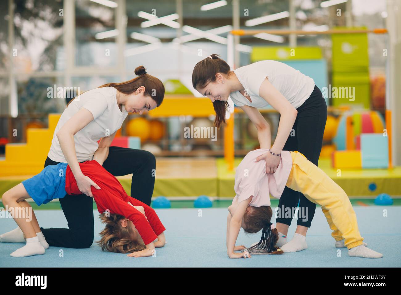 Kids doing exercise bridge in gym at kindergarten or elementary school. Children sport and fitness concept. Stock Photo