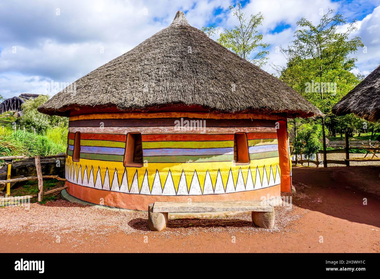 Traditional African house with multicolored painted walls and a bench in front of the house Stock Photo