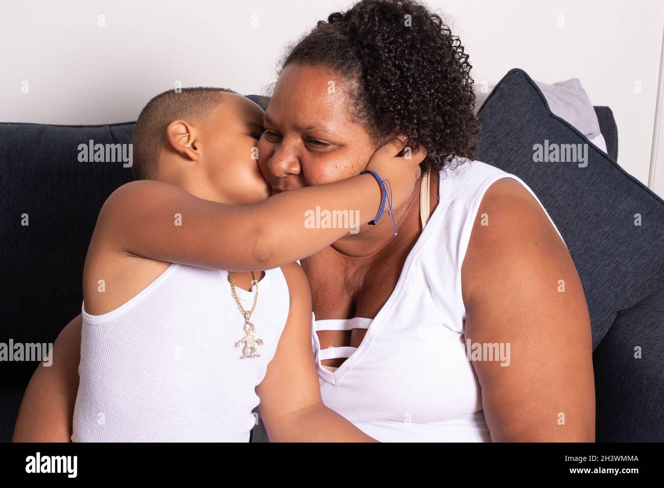 5 year old boy giving his grandmother a kss, sitting on couch Stock Photo