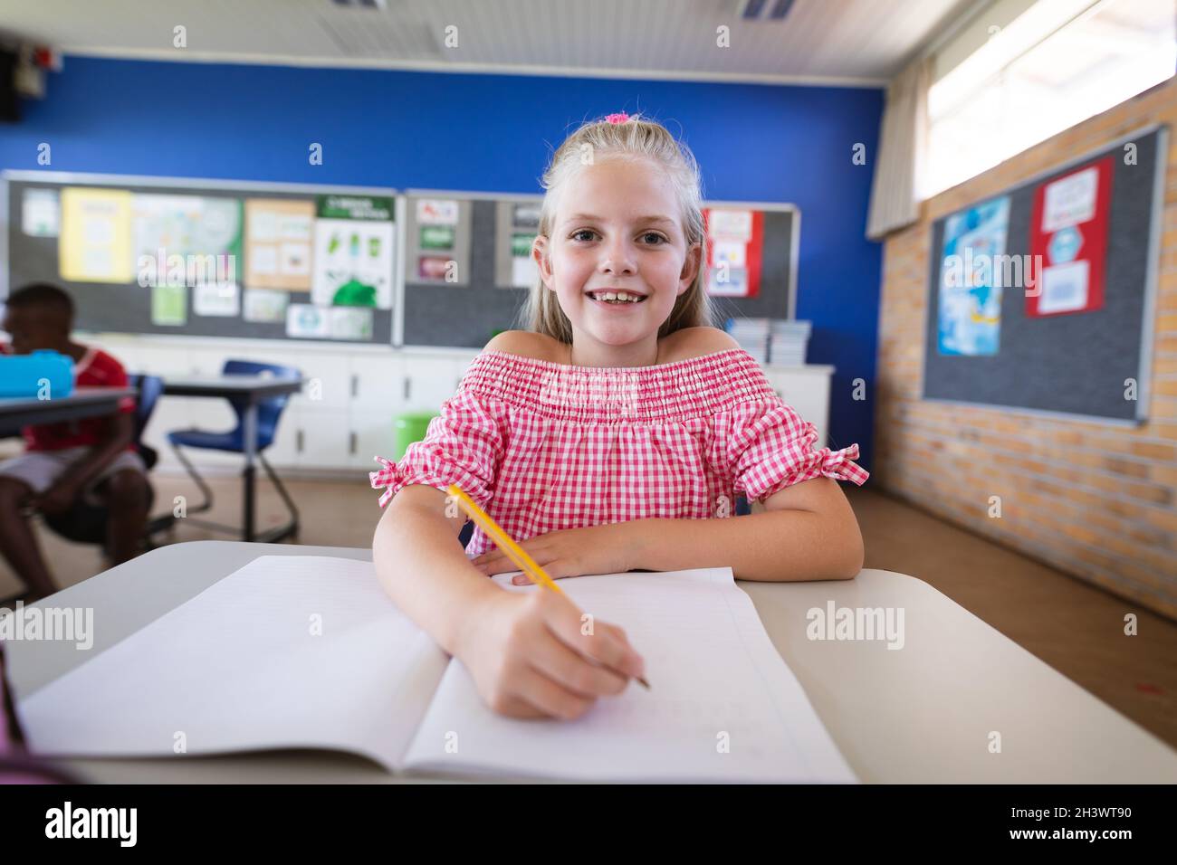 Portrait of caucasian girl smiling while sitting on her desk in the ...