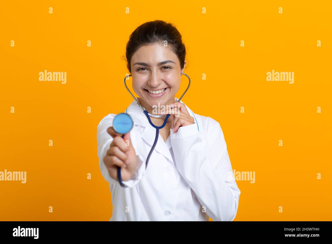 Portrait of indian doctor woman in white medical gown isolated on yellow background Stock Photo