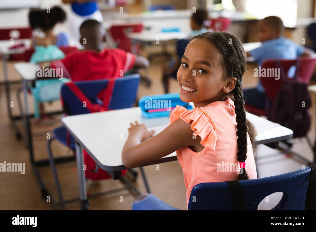 Portrait of african american girl smiling while sitting in the class at ...