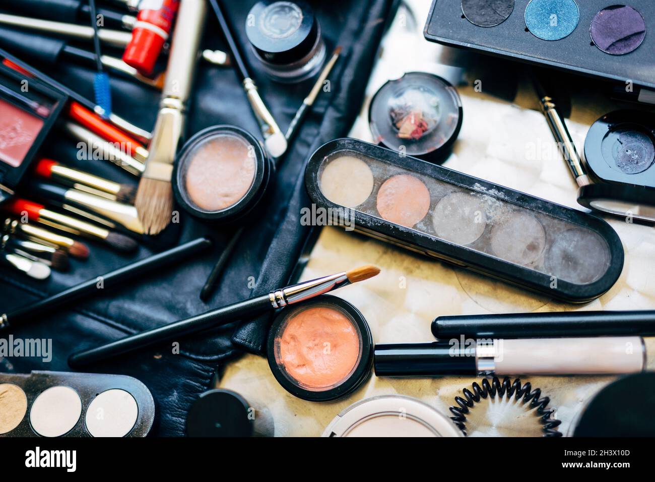 Professional set for applying makeup with brushes, eyeshadow palette and mascara scattered on the table. Makeup artist set. Stock Photo