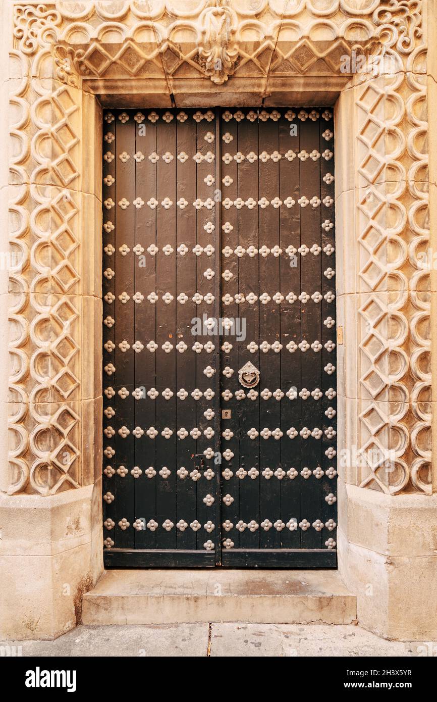 Brown doors with rivets in the arch with original molding Stock Photo