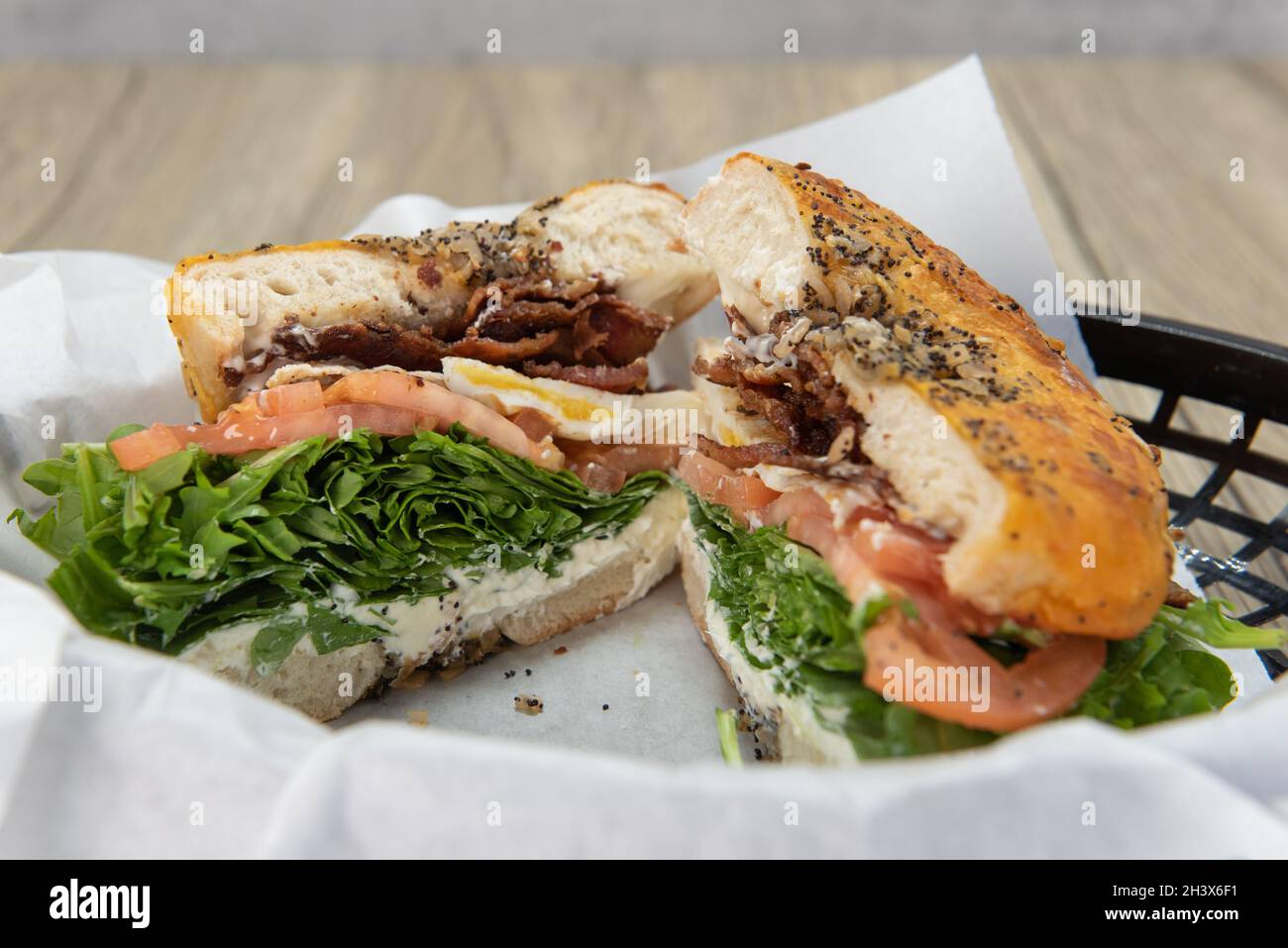 Tasty and hearty breakfast bagel BLT sandwich cut in half to show the bursting ingredients of bacon, lettuce, and tomato. Stock Photo