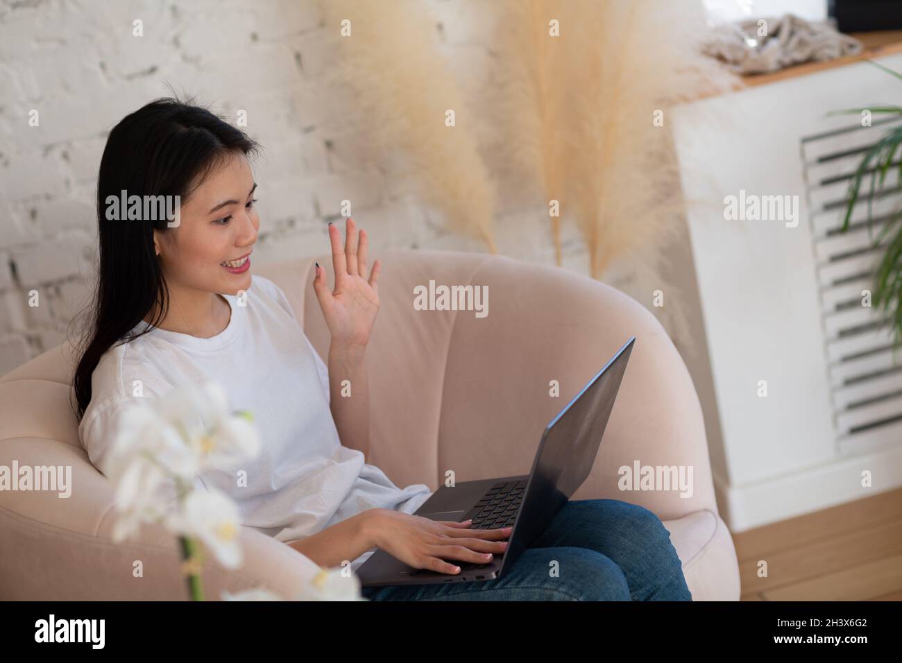 Portrait of asian woman enjoying using laptop at apartment interior indoor living room. Video call webinar stream concept. Stock Photo