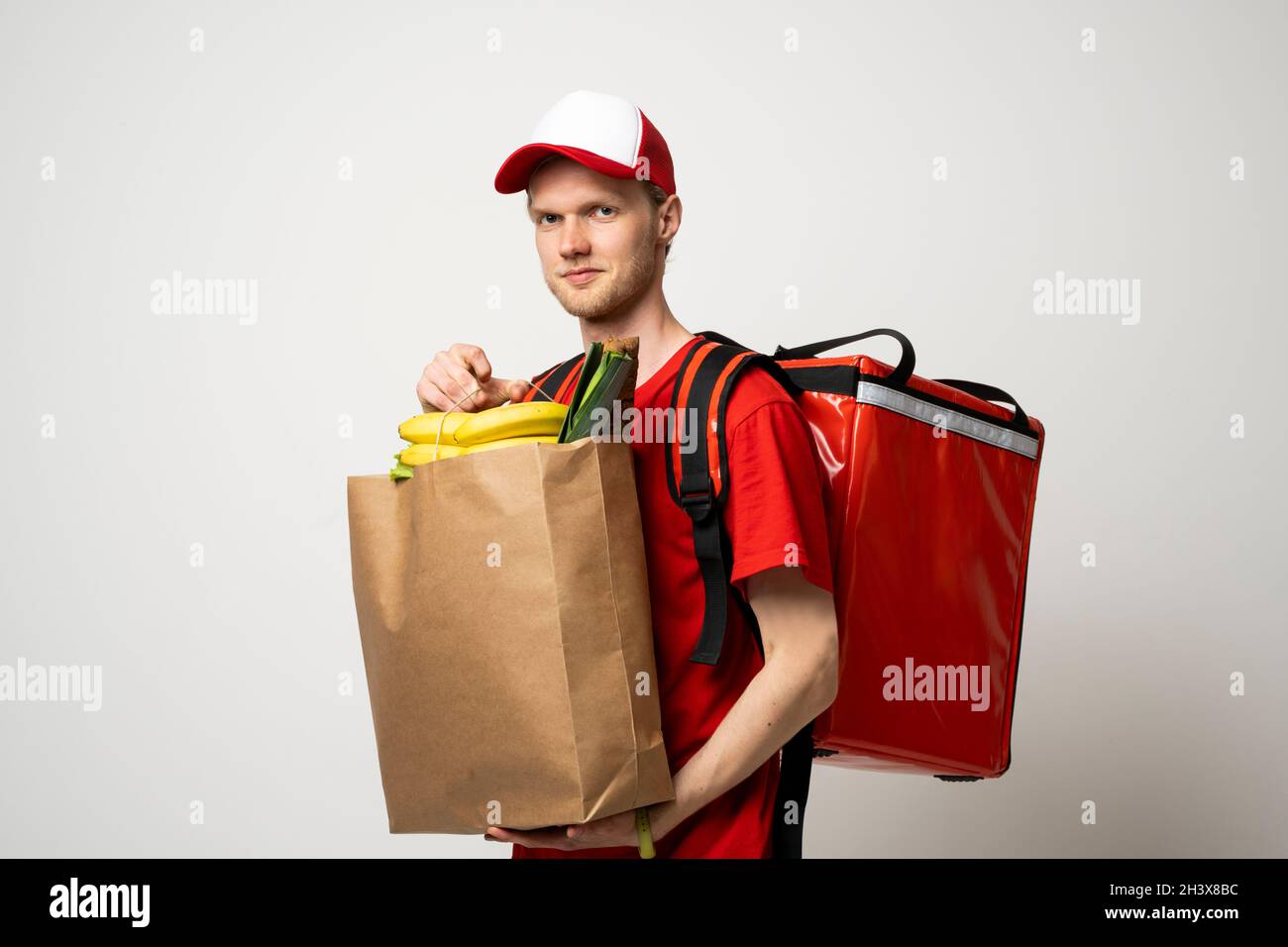 Delivery Concept Handsome delivery man in a red uniform with thermal