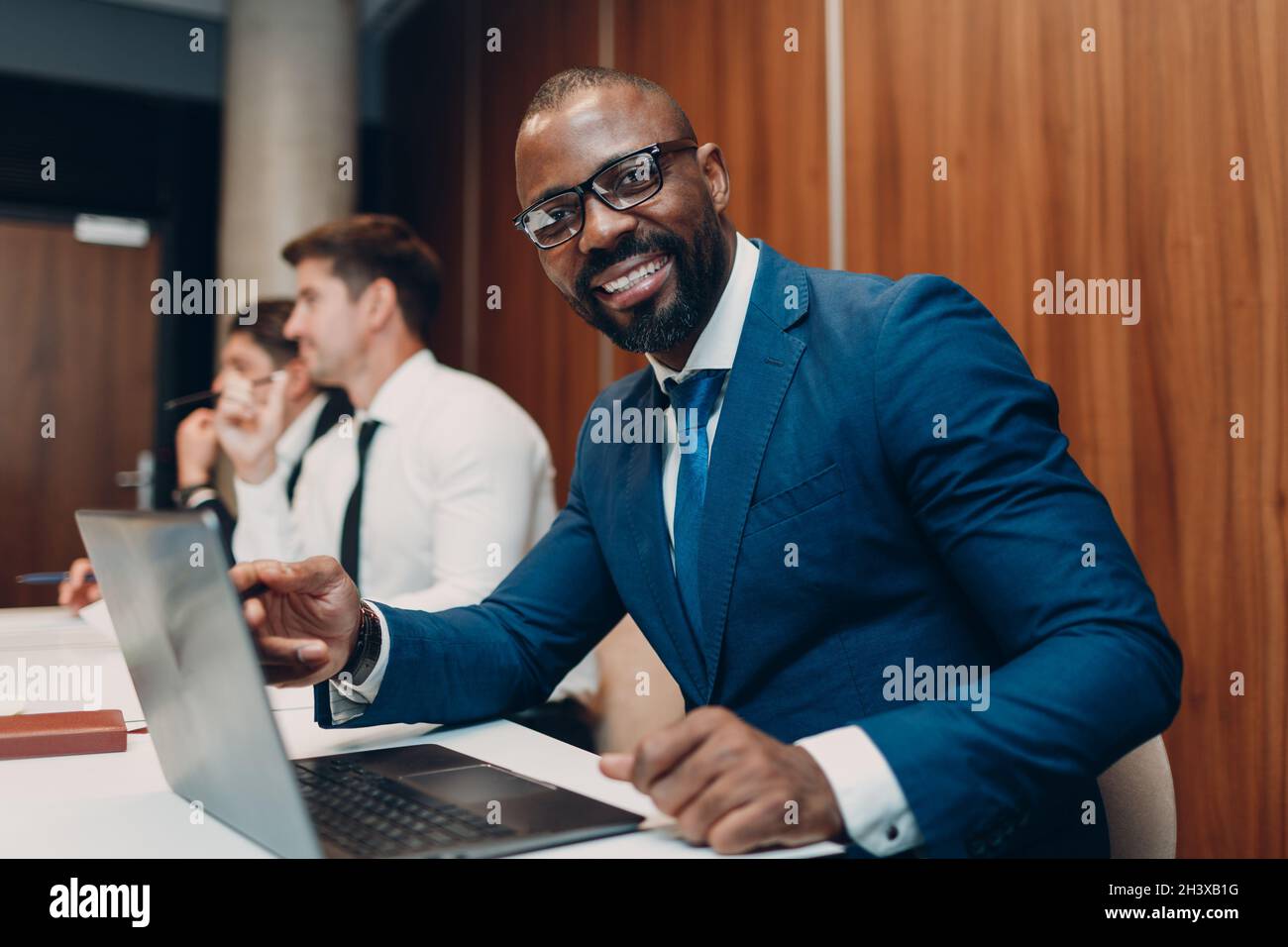 African american black man businessman sitting at table with laptop on office team people background. Stock Photo