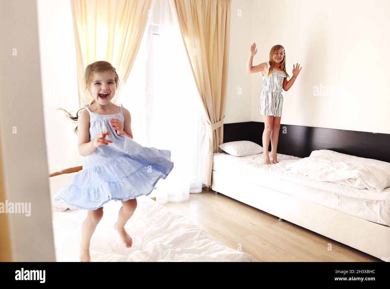 Two cute carefree little sisters girls in casual clothes playing having fun in childrens room Stock Photo