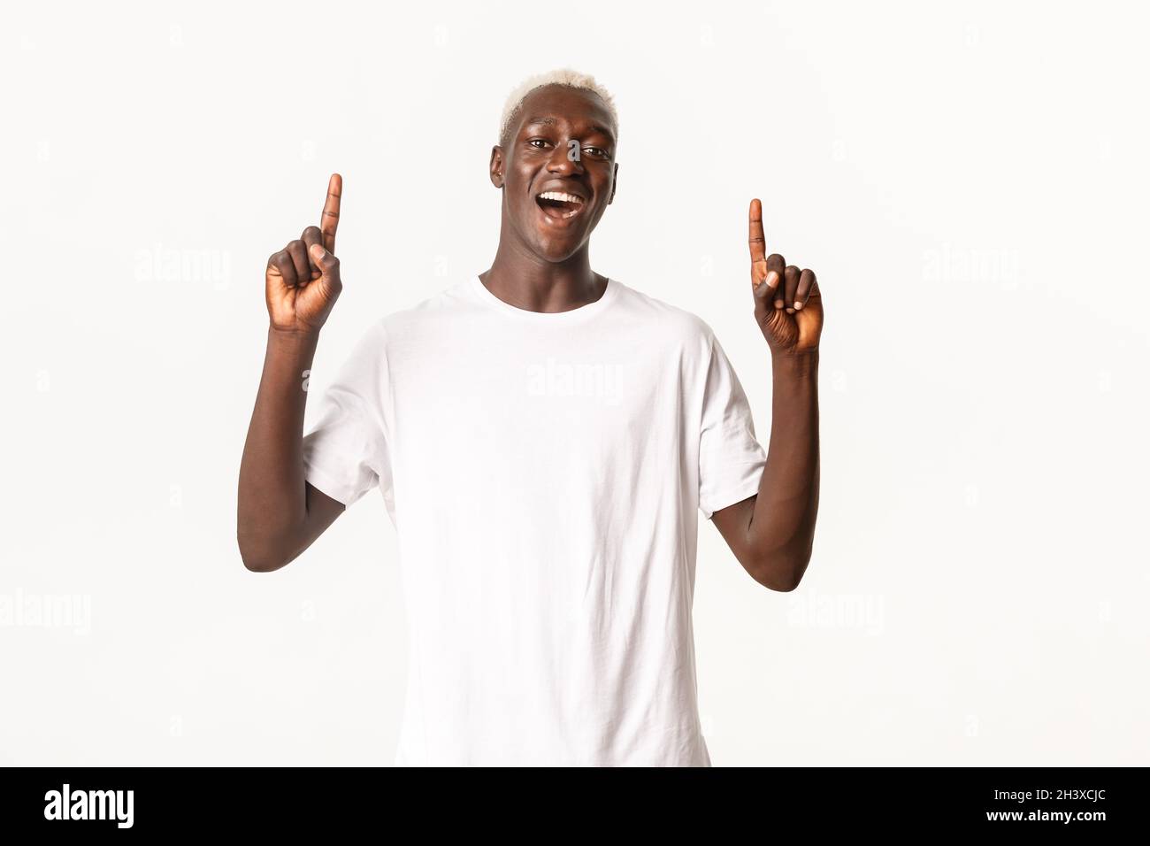 Portrait of cheerful african-american blond guy, pointing fingers up ...