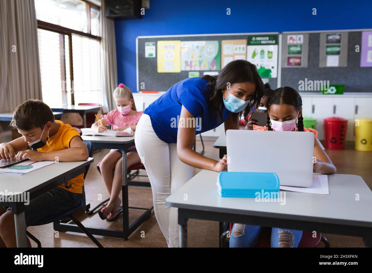 African american female teacher wearing face mask teaching a girl to ...